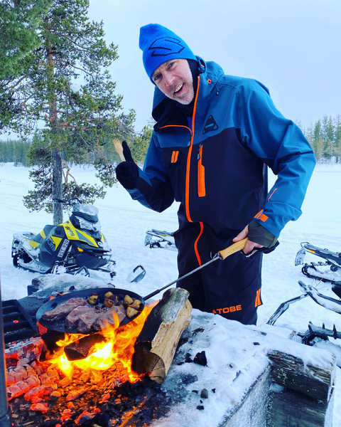 Guide einer Schneemobil Skidoo bei grillen des Mittagessens auf dem Lagerfeuer.