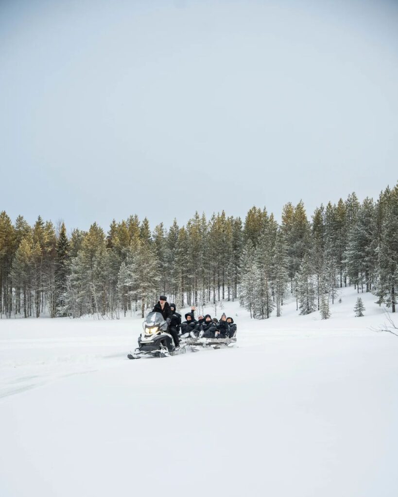 Schneemobil bringt Gruppe von Gästen auf den See. Schneemobiltour