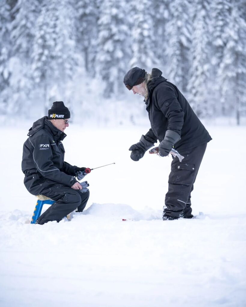 Zwei Männer angeln im Winter auf einem See.